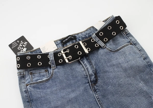 Detail of a blue denim fabric featuring a black double-grommet eyelet canvas belt