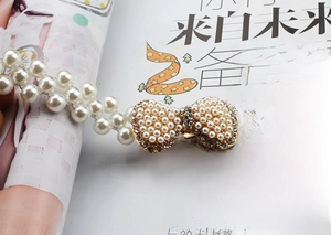 Macro detail of elastic pearl waist chain with rhinestone bow buckle on magazine