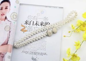 Close-up of elegant pearl waist chain with a sparkling rhinestone bow buckle detail