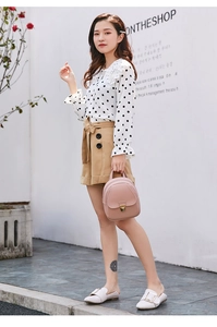 Fashionable model posing with a pink mini backpack, white polka dot blouse and shorts