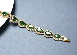Détail d'un bracelet doré avec cristaux verts en goutte et strass scintillants
