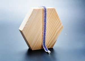 Macro detail of multi-row bracelet with sparkling blue and clear gemstones on wood