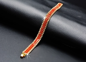 Detailed macro view of gold-plated bracelet with red and clear rhinestones on leather