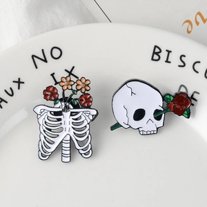 Creative dark skull and ribcage enamel pins with roses on a white porcelain dish
