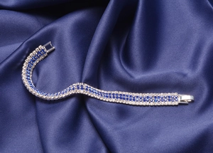 Close-up of silver tennis bracelet with blue and clear crystals on blue silk