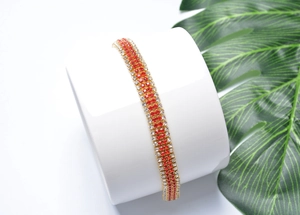 Close-up of dual-layer gold-plated bracelet featuring red and white rhinestones on ceramic