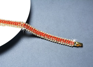 Detailed close-up of a multi-row gold bracelet with sparkling red and clear rhinestones