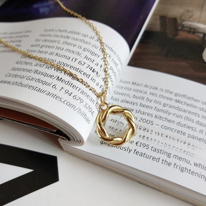 Detail shot of a twisted gold wreath pendant necklace resting on an open book page