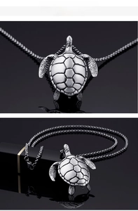 Detail of vintage tortoise pendant with textured shell on black reflective surface