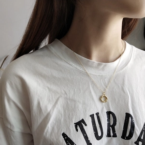 Detail of a gold double-intertwined ring pendant necklace worn on a white t-shirt
