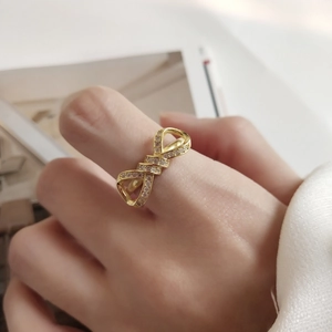 Minimalist gold bow ring with sparkling zircons shown on a model's hand in soft light