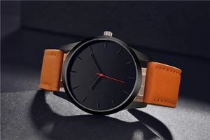 Detail of minimalist black watch dial with red second hand and brown leather strap