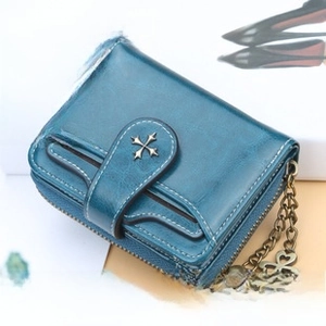 Detail of teal leather women's wallet with clover charm and star-shaped metal emblem