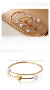 Detailed view of woven titanium steel bracelets with shell pearls and heart charms in three tones