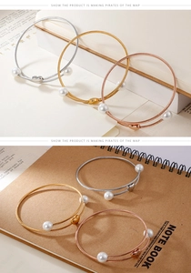 Detail of cable wire bangles in silver, gold, and rose gold with heart and pearls