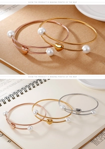 Detailed view of layered heart charm bracelets with pearls in gold and silver finishes