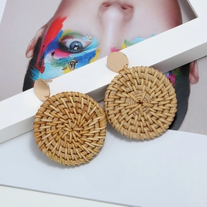 Gros plan de boucles d'oreilles rondes en rotin tressé avec clous en métal doré