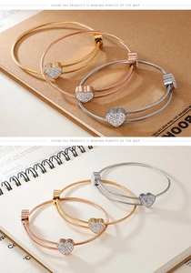 Detail of three-tone twisted wire bracelets with sparkling heart pendants in gold and silver