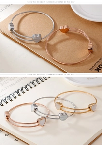 Macro detail of twisted steel bracelets with heart mother of pearl charms in three colors