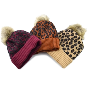 Detailed view of leopard print knit beanies with faux fur pom-poms in various colors
