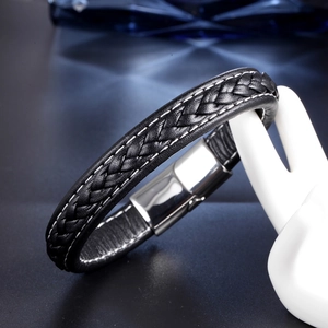 Close-up of black braided leather bracelet with white stitching and silver magnetic clasp