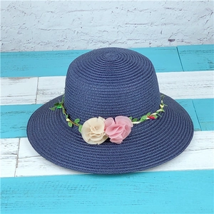 Navy blue woven straw sun hat decorated with pink and white floral vine accents