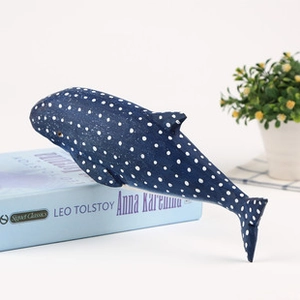 Gros plan d'une baleine en bois bleue à pois blancs posée sur un livre décoratif