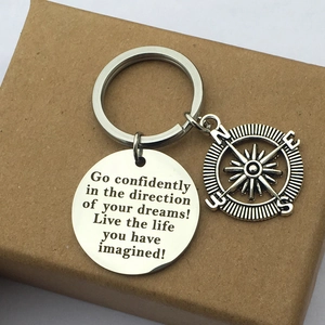 Detail of engraved stainless steel compass keychain with motivational quote on kraft box