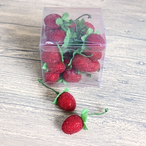 Lifelike artificial red strawberry models with green stems in a clear plastic display box