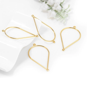 Golden teardrop metal pendants for DIY jewelry making on a minimalist white tray
