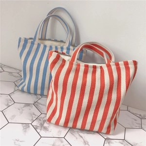 Detailed view of striped canvas tote bags in blue and orange with durable fabric handles