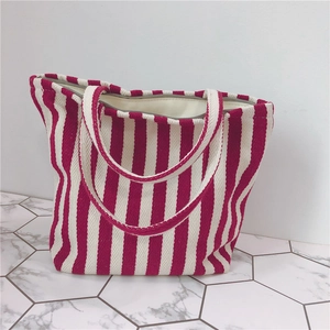 Close-up of red and white striped canvas tote bag with zipper on marble floor