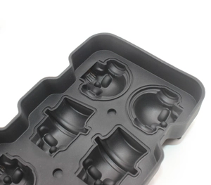 Detail of dark gray silicone mold featuring stylized robot head cavities for ice or chocolate