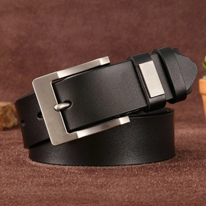 Close-up of black genuine leather belt with silver pin buckle on brown textured surface