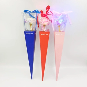Close-up of glowing artificial gold foil roses in blue, red, and pink gift boxes