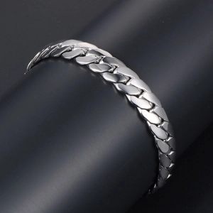 Polished silver stainless steel Cuban link bracelet for men displayed on a curved stand