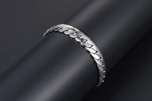 Macro view of polished stainless steel Cuban link bracelet on a premium black display