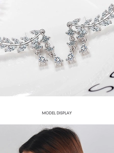 Macro detail of silver tassel earrings featuring marquise-cut zircon wing elements