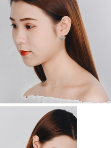 Detailed view of silver dragonfly stud earrings with rhinestones on female model