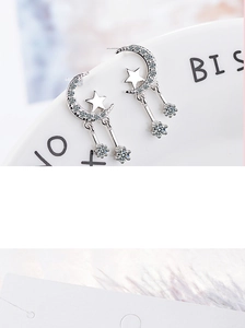 Detailed view of silver moon and star drop earrings with inlaid sparkling cubic zirconia