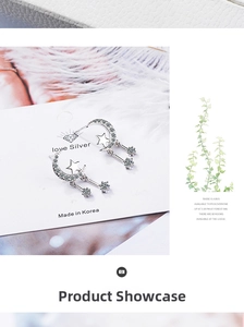 Detail of silver moon and star drop earrings with zircons on white jewelry card