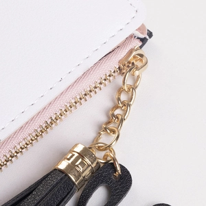 Detail of white leather wallet showing neat stitching, pink zipper and black leather tassel