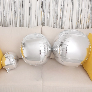 Three-piece set of silver mirror finish 4D round balloons in various sizes on a sofa
