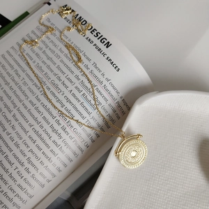 Macro shot of gold-plated 925 silver round sunburst pendant on a vintage art book