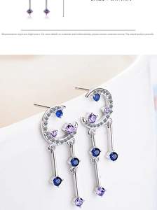 Detail of silver crescent moon earrings with blue purple stones and tassels