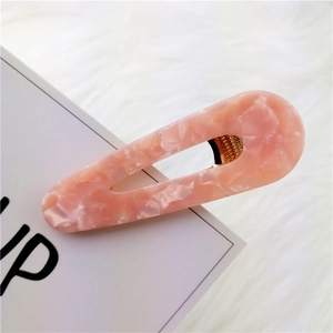 Detailed view of pink marble acetate hair clip on soft white plush fabric background