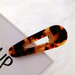 Close-up of tortoise shell pattern acetate drop-shaped hair clip on soft white plush