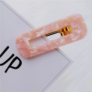 Detailed shot of pink marble pattern acetate hair clip with gold metal fastener