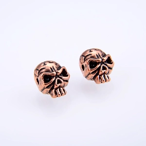 Detailed macro view of vintage bronze skull stud earrings with aged metal texture