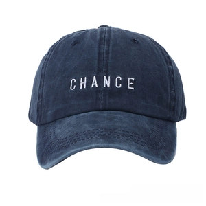 Detailed view of white CHANCE embroidery on a dark blue washed cotton baseball cap